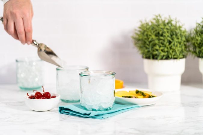 Main remplissant des verres de glaçons canards pour des boissons rafraîchissantes.