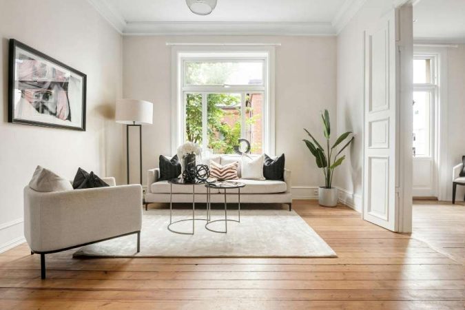 Un tapis uni de couleur claire posé sur un parquet en bois massif, complétant parfaitement le choix d'un tapis pour un salon chaleureux au style épuré.