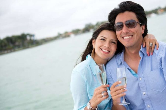 Un couple profite d'un voyage romantique en trinquant avec des coupes de champagne près de l'eau.