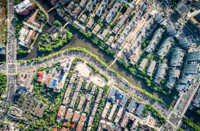 Vue aérienne d'une ville traversée par une rivière pour illustrer le prix m2 vs rendement locatif ville.